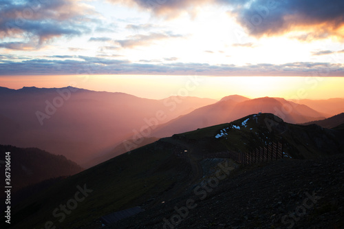 Sunset in the mountains. Autumn scenery with forest, clouds and little snow. Warm gradient colors