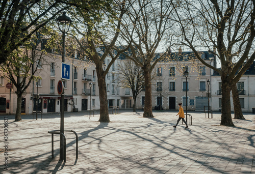 Masked woman walking through empty place in a French town during the coronavirus crisis