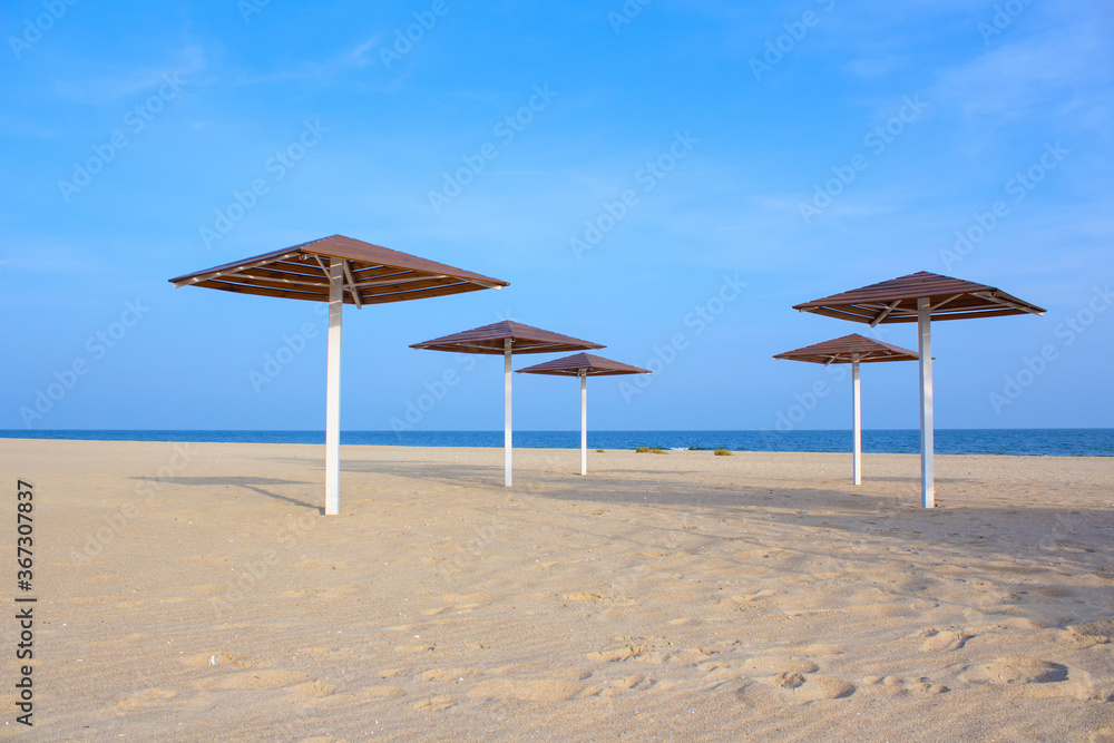 Umbrellas on the empty sandy beach . Coast without vacationers