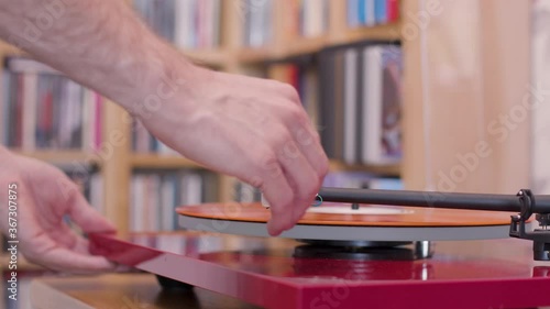 Putting an orange vinyl lp on a record player and playing it close up photo