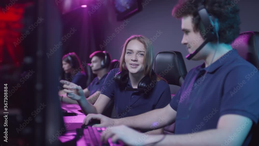 Young Caucasian woman and her male friend spending time together in cybersport club talking about game Young Caucasian woman and her male friend spending time together in cybersport club talking about game