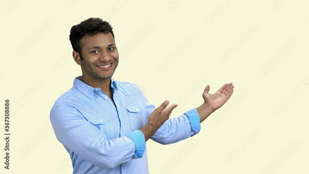 Cheerful dark-skinned businessman showing empty copy space. Smiling man presenting product on white background. Cheerful dark-skinned businessman showing empty copy space. Smiling man presenting product on white background.