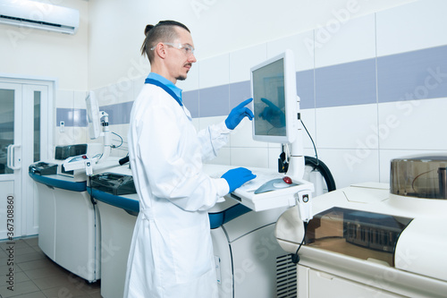 Laboratory assistant in rubber gloves working with a modern immunochemistry analyzer