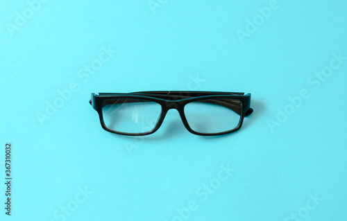 Glasses in black frames on a blue background. Eye health concept.