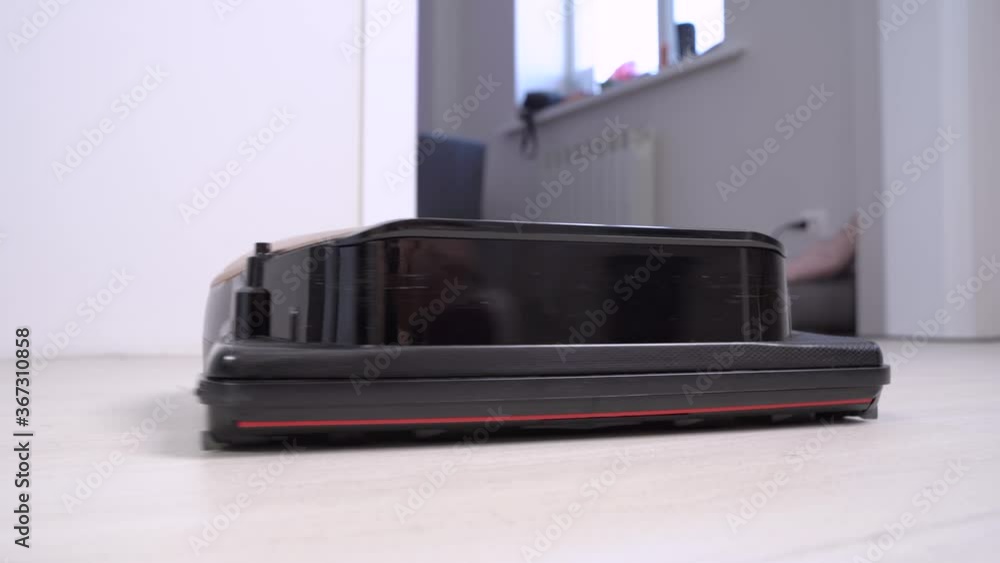 Black robot vacuum cleaner at home, standing on the floor and rotating from side to side like following on something. Humor concept of clever equipment for housekeeping. Black robot vacuum cleaner at home, standing on the floor and rotating from side to side like following on something. Humor concept of clever equipment for housekeeping.