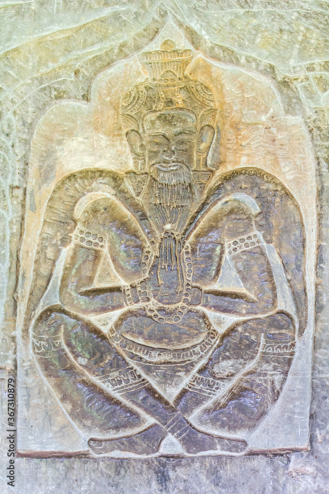 Carved Bas Relief of praying man sitting with his legs crossed,  in Angkor Wat in Siem Reap, Cambodia