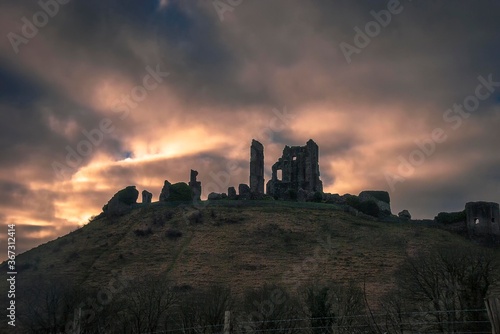 The sun rises behind the ruins of Corfe Castle in Dorset, UK