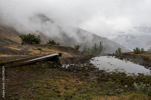 A beautiful mountain lake against with heavy foggy. A small lake in the mountains against the background of fog. A puddle of rain in the mountains. Mountains in the fog