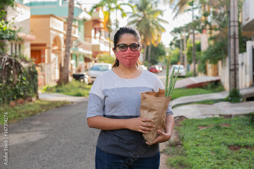 Young Indian woman with grocery bag bought from local vendors near home. No hoarding, only buying basic required amounts of groceries, the new normal