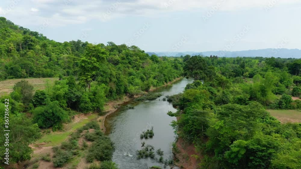The lush tropical trees around the Nam Theun in Asia, Laos, Khammouane, towards Thakek, on a sunny day. The lush tropical trees around the Nam Theun in Asia, Laos, Khammouane, towards Thakek, on a sunny day.