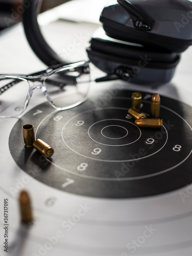 Shooting target with ammunition, pistol, ballistic glasses and headphones