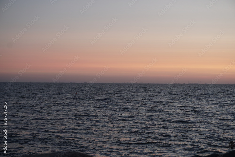 orange sunset, dark, still water, perfectly straight horizontal line, evening