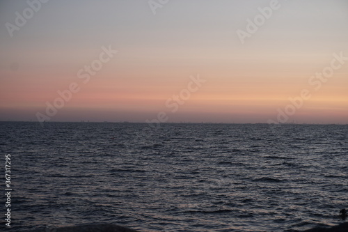 orange sunset  dark  still water  perfectly straight horizontal line  evening