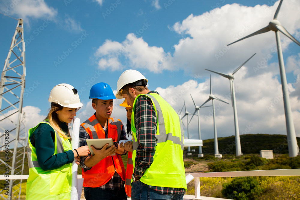 Young workers looking and checking wind turbines at field Young workers looking and checking wind turbines at field
