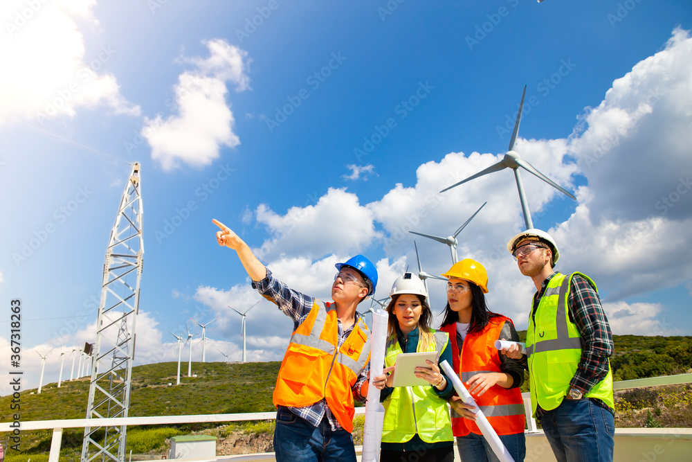 Young workers looking and checking wind turbines at field Young workers looking and checking wind turbines at field