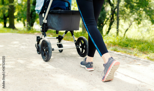 Young active mother doing her exercises with stroller on a walk
