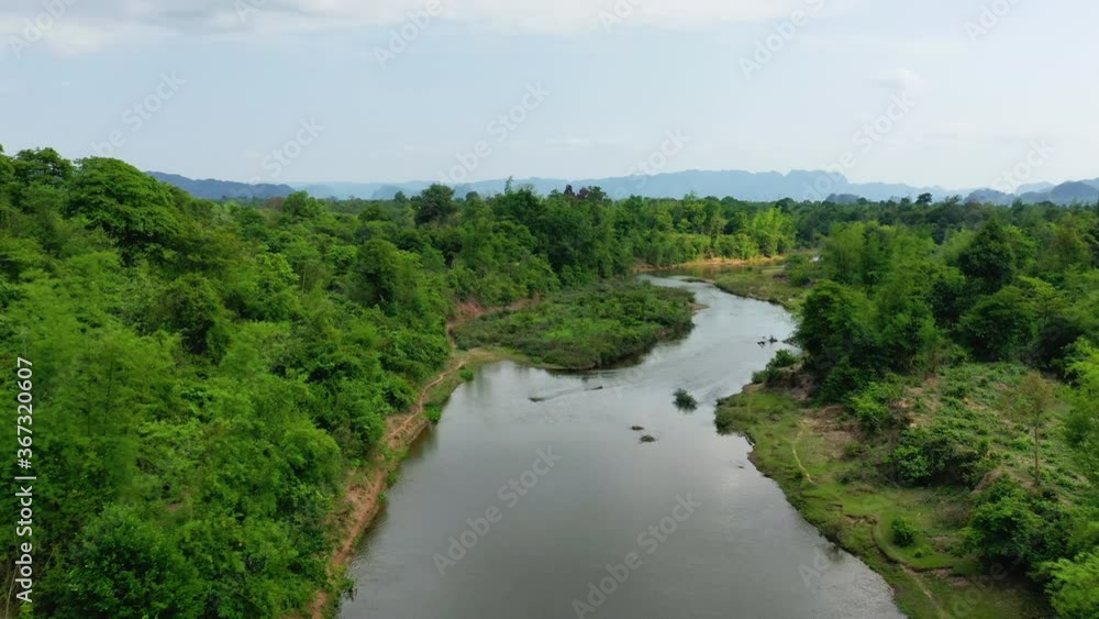 The Nam Theun surrounded by green trees in the countryside in Asia, Laos, Khammouane, towards Thakek, on a sunny day. The Nam Theun surrounded by green trees in the countryside in Asia, Laos, Khammouane, towards Thakek, on a sunny day.