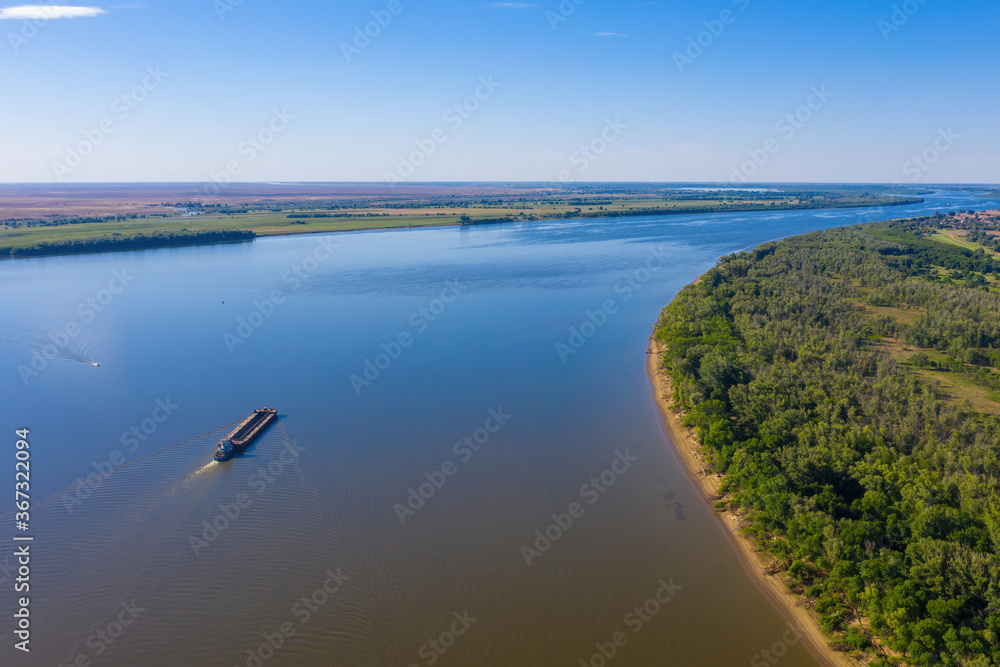 A barge or dry cargo ship goes upstream of the Volga River near Astrakhan. Aerial photography. High quality photo