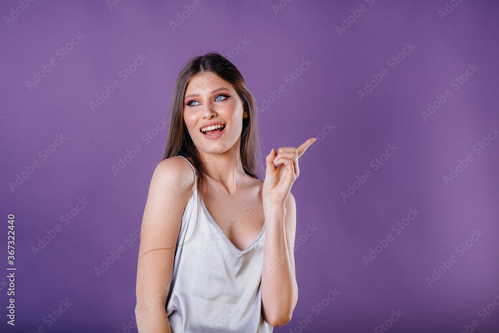 A young beautiful girl shows emotions and smiles in the Studio on a purple background. Girls for advertising A young beautiful girl shows emotions and smiles in the Studio on a purple background. Girls for advertising