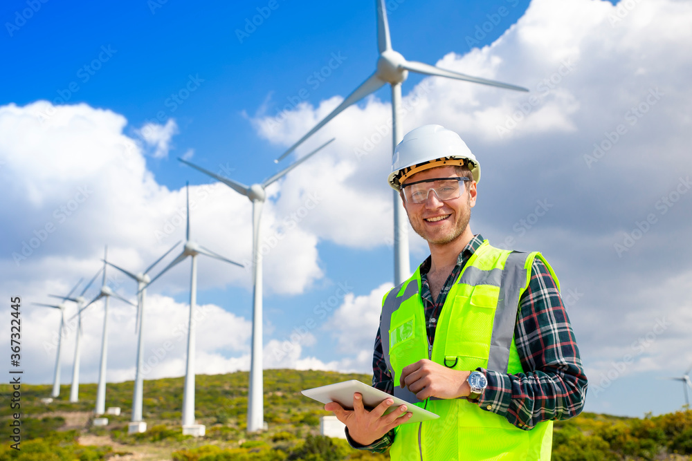 Young worker looking and checking wind turbines at field Young worker looking and checking wind turbines at field