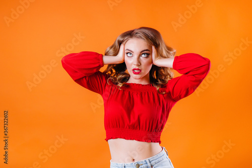 A young beautiful girl shows emotions and smiles in the Studio on an orange background. Girls for advertising