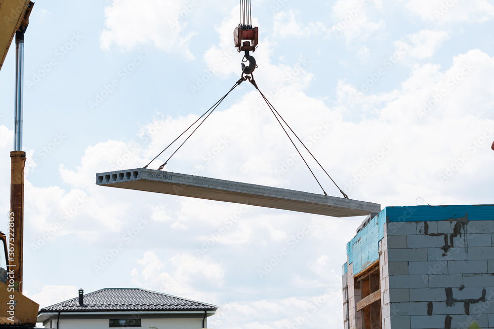 Builder worker installing concrete floor slab panel at building construction site