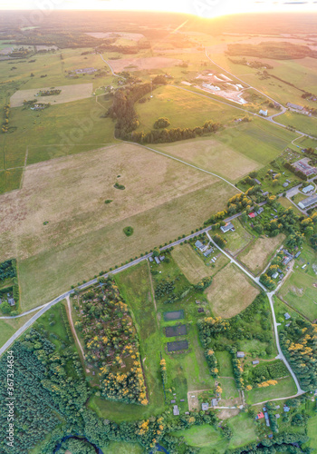 Beautiful sunset over the small town. Fields and trees around. Aerial photography.