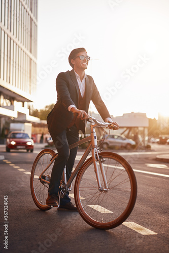 Positive businessman riding bike in evening