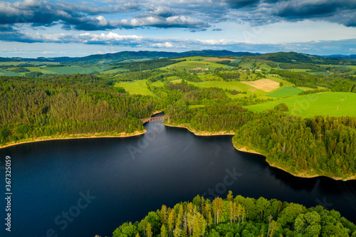 Aerial view of beautiful lake with islands and green forests in mountains on a sunny summer day in Pilchowice  Lower Silesia  Poland. Drone photography