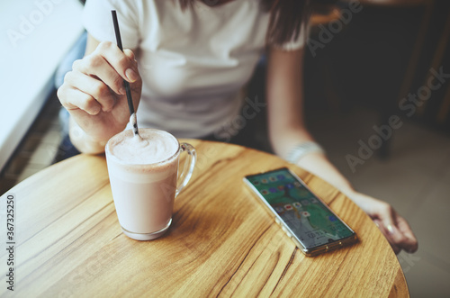 Woman drink pink matcha latte with milk.Relaxation mood.Smart phone on table. Blurred image,selective focus
