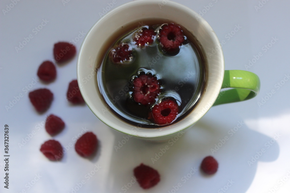 Summer cup of tea with red raspberries on white background Summer cup of tea with red raspberries on white background