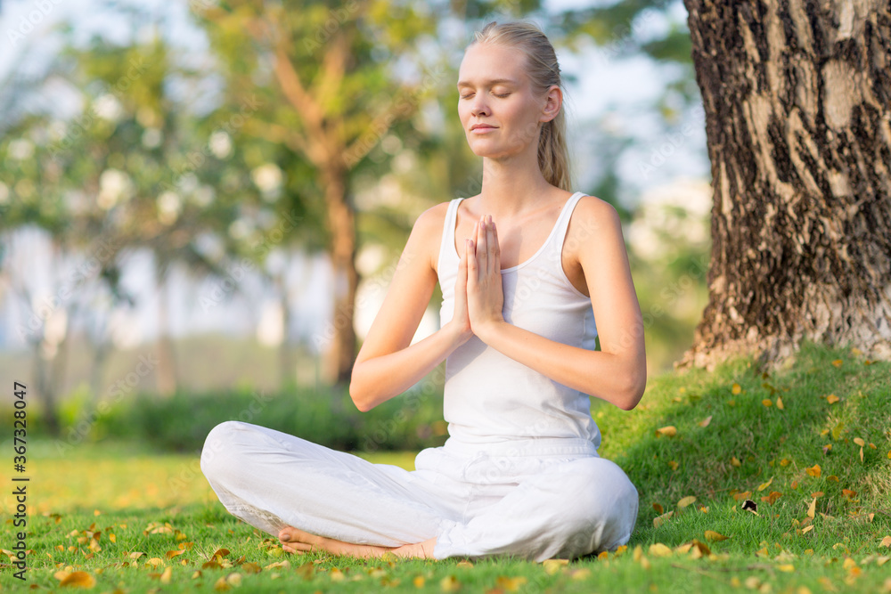 Serene calm female adult practicing meditation and yoga at peace outside in the nature. Health, wellness and self care.