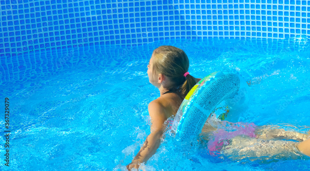 girl swims in the pool in an inflatable ring - summer vacation at home