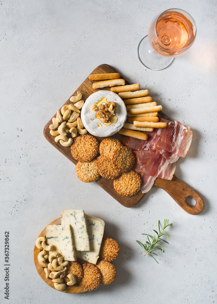 Wooden board with cheese, ham, bread stick, nut cashew, walnut and honey on camembert with glasses of wine on white background Wooden board with cheese, ham, bread stick, nut cashew, walnut and honey on camembert with glasses of wine on white background