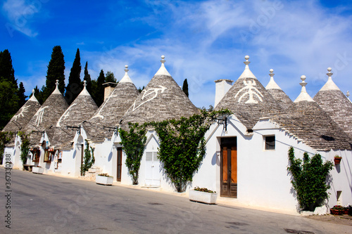 Row of typical trulli houses in Alberobello, Puglia, Italy. Traditional symbols are painted on the conical roofs. A trullo is a traditional Apulian stone dwelling in Itria Valley. 