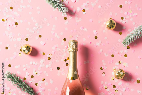 Bottle of rose champagne wine with gold balls and christmas tree branches