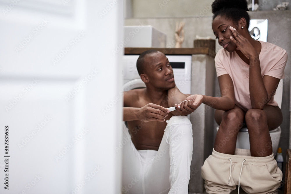 Fototapeta premium happy african couple found out that woman is pregnant, they use pregnancy test, future relatives sit in toilet together, smile