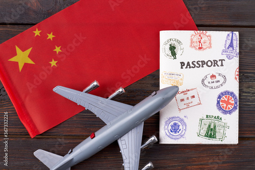 Travel to China concept. Chinese flag with passport and toy airplane on wooden table.