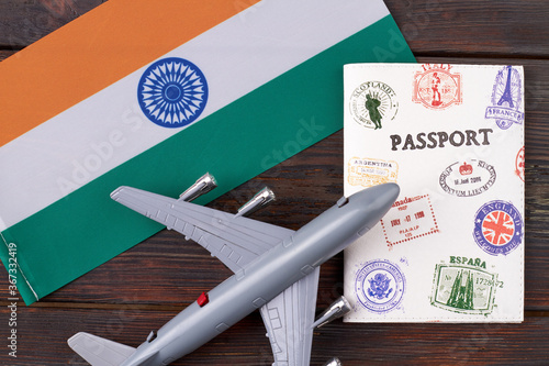 Flat lay concept of flight to India. Top view airplane model with flag of India and travel passport on wooden table.
