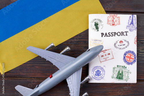 Flight to Ukraine concept. Ukraninan blue and yellow flag with airplane model and travel passport on wooden table. Top view flat lay.