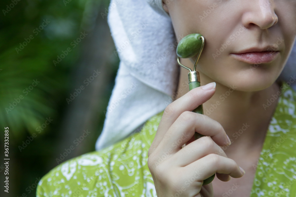 Face massage. Woman using jade face roller for skin care. Face massage. Woman using jade face roller for skin care.