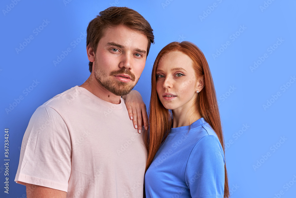 confident caucasian couple posing, isolated in studio with blue background, they seriously look at camera. love, people, relationships concept confident caucasian couple posing, isolated in studio with blue background, they seriously look at camera. love, people, relationships concept