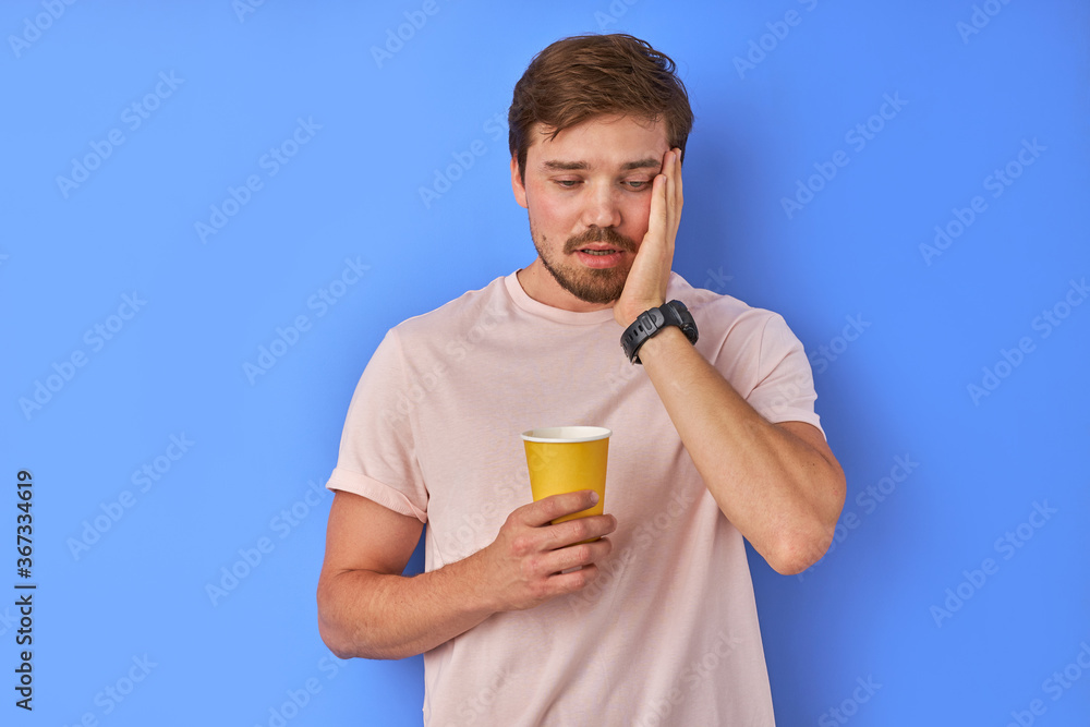 exhausted guy drinking coffee isolated in studio, man tired to work, he wants some rest. blue background exhausted guy drinking coffee isolated in studio, man tired to work, he wants some rest. blue background