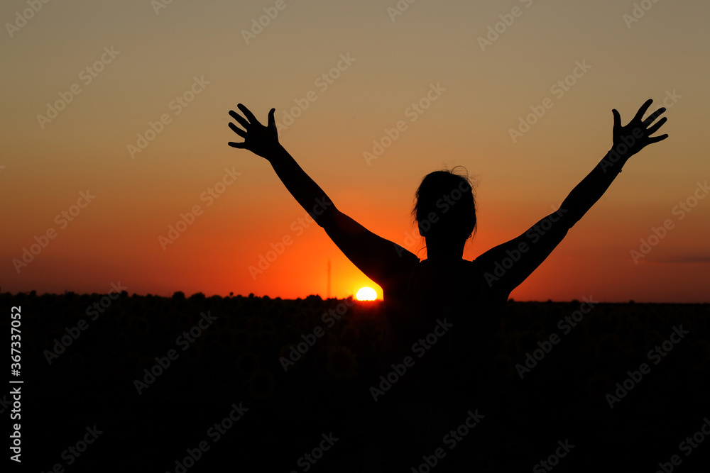 silhouette of a girl showing signs with her hands photographed at sunset