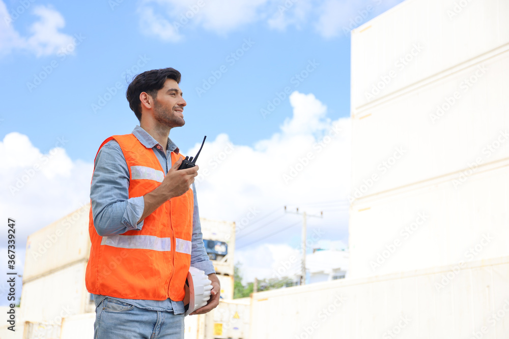 A engineering working at container stock yard, radio mobile talking communication with loader forklift for transport control handling