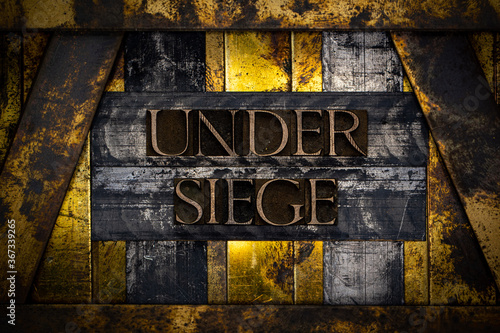 Fotografie Under Siege text formed with real authentic typeset letters on vintage textured
