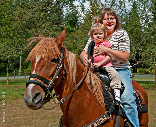 This Caucasian grandma has her toddler 2 year old granddaughter with her riding a Peruvian Passo horse in this country family stock image.