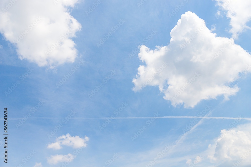 Light blue sky with fluffy white clouds. Airplane trails on blue sky. Contrails in the sky. Sky with traces Light blue sky with fluffy white clouds. Airplane trails on blue sky. Contrails in the sky. Sky with traces