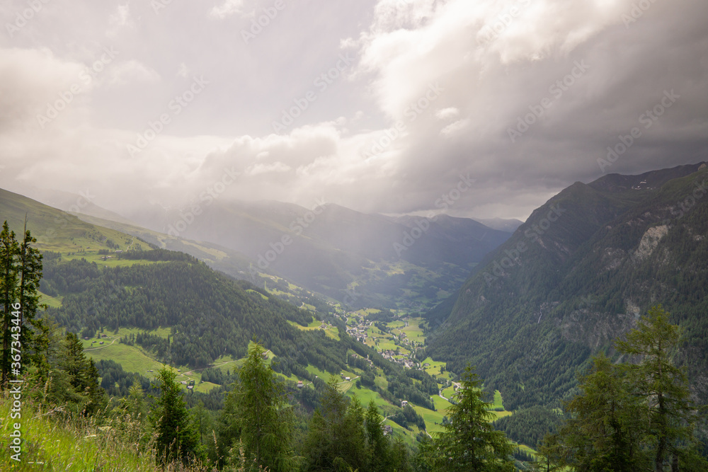 Obraz premium cloudy mountains in Austria with trees in the foreground