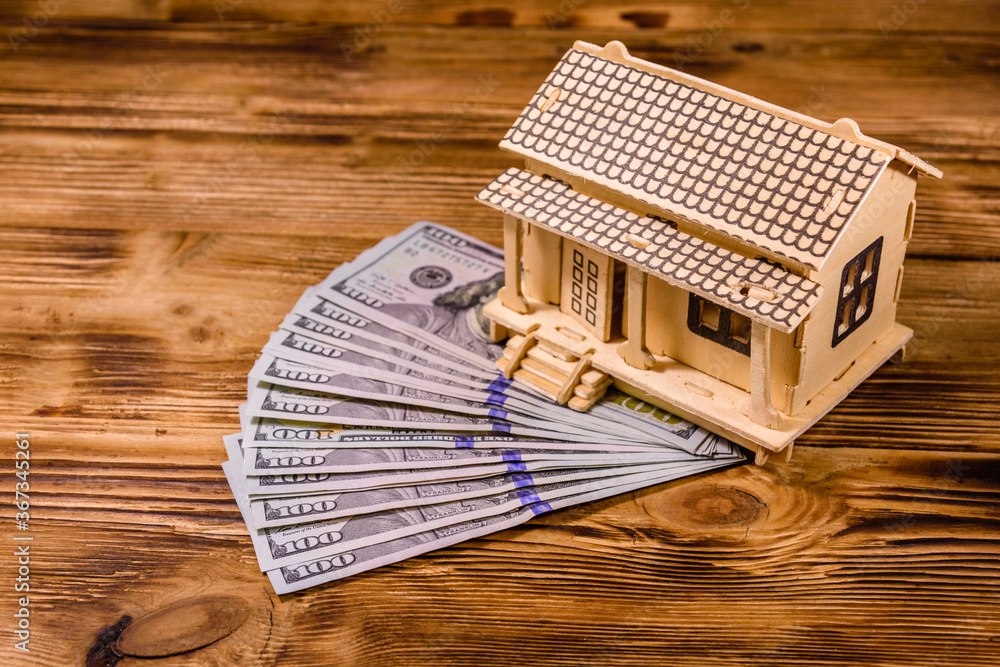 Plywood model of the house and one hundred dollar banknotes. Loan, real estate concept Plywood model of the house and one hundred dollar banknotes. Loan, real estate concept